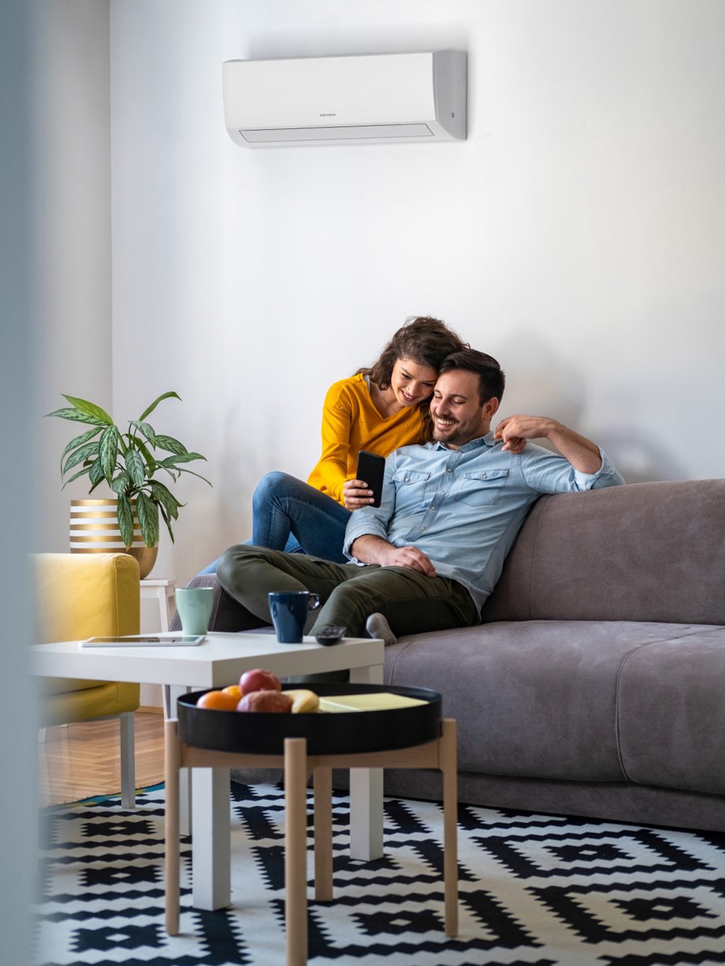 Airco boven een zithoek met twee bewoners op de sofa