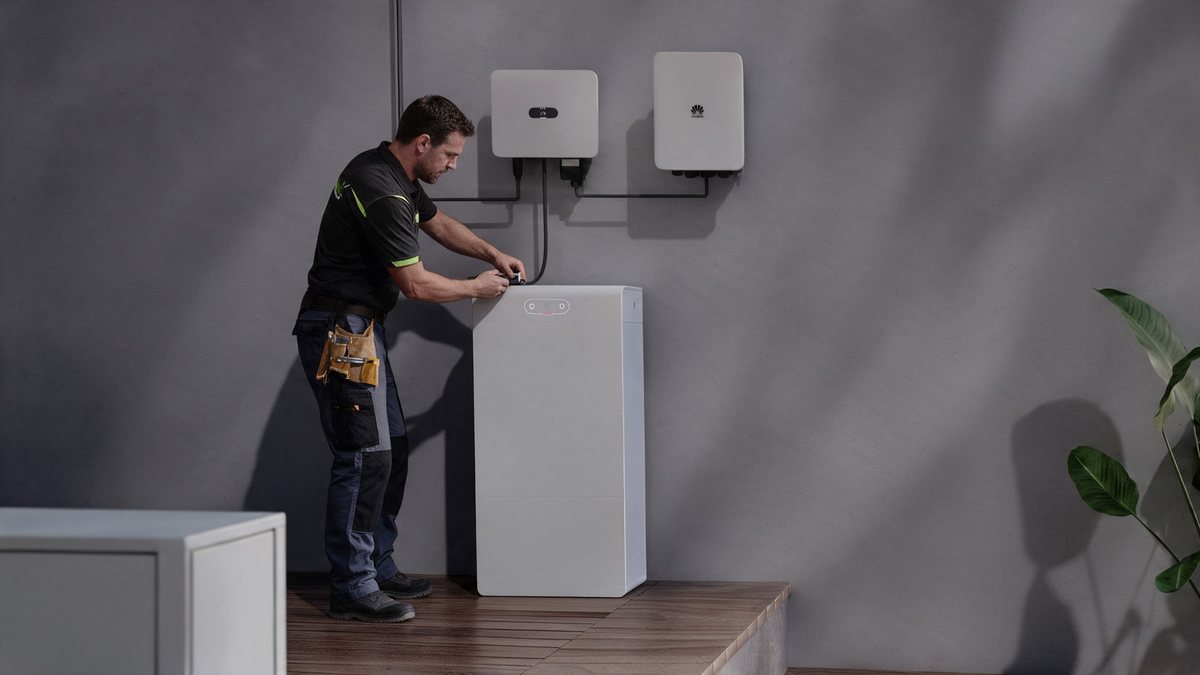 Technicus sluit een thuisbatterij aan naast de omvormers
